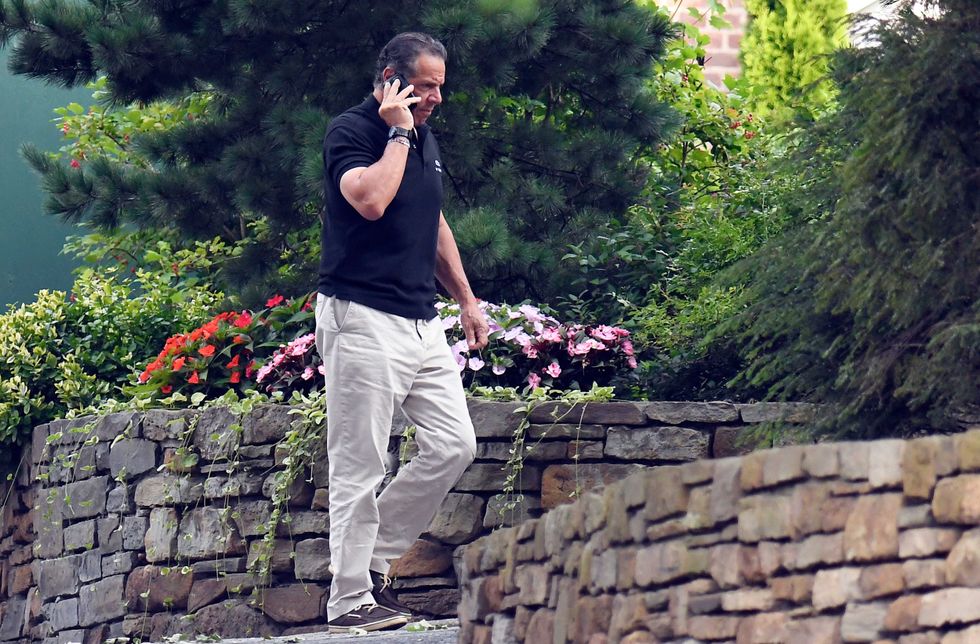 Gov. Andrew Cuomo talks on the phone while walking with his dog Captain at the New York state Executive Mansion, Saturday, Aug. 7, 2021, in Albany, N.Y