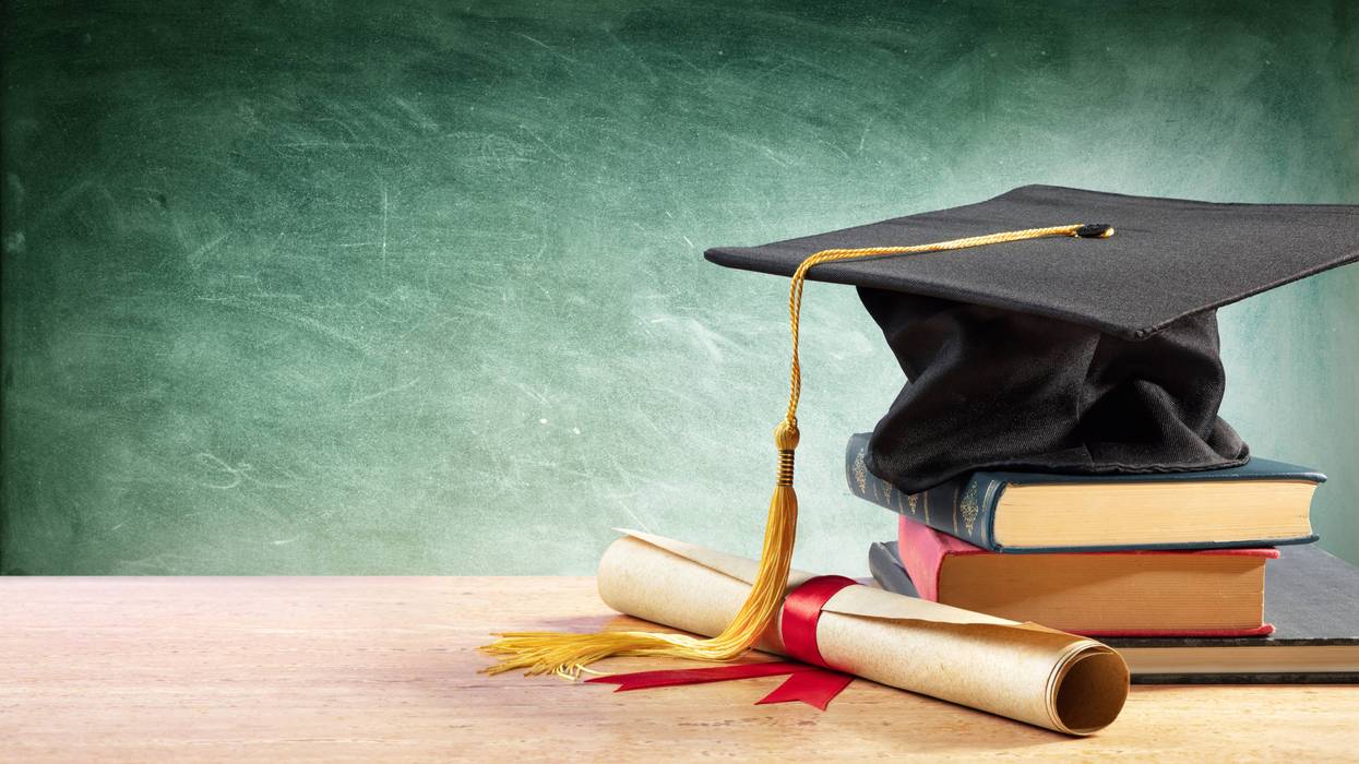Graduation cap and diploma on a table with books