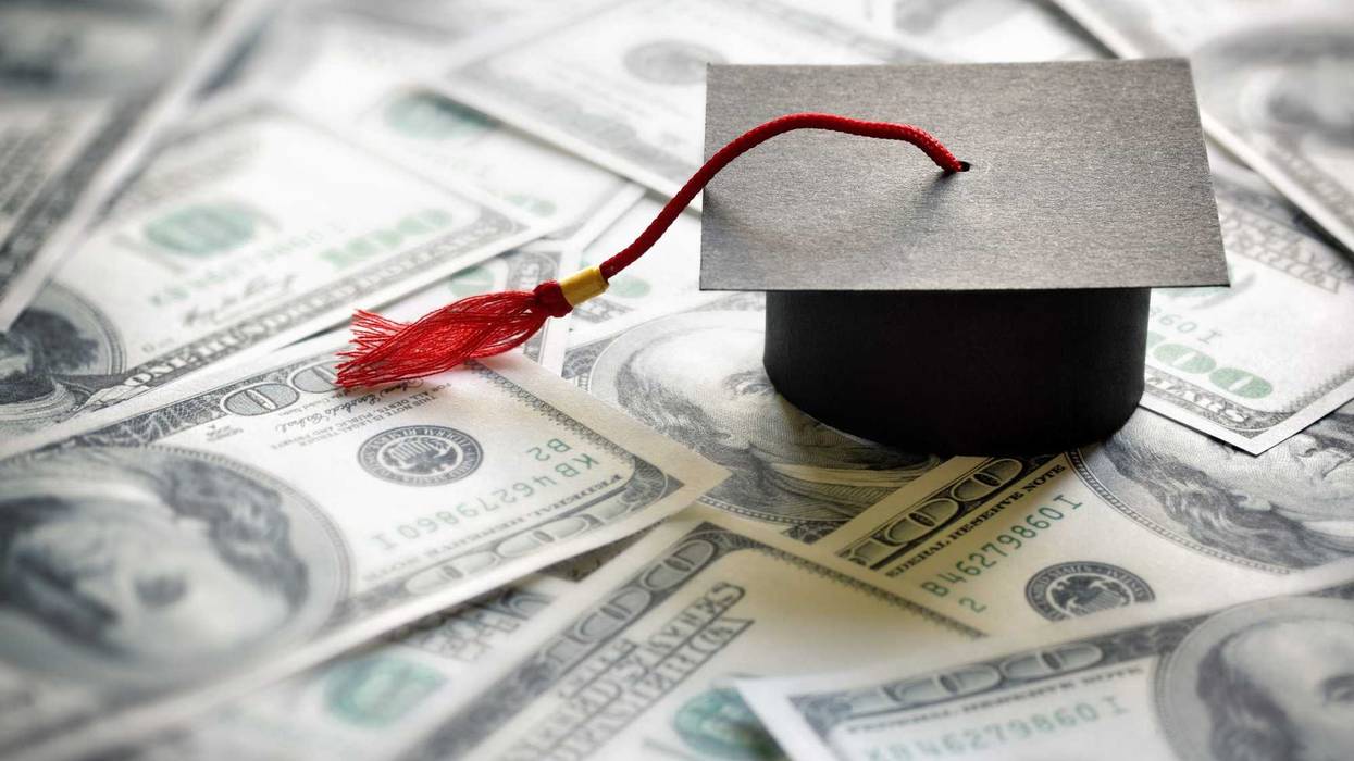 Graduation cap on top of hundred dollar bills.