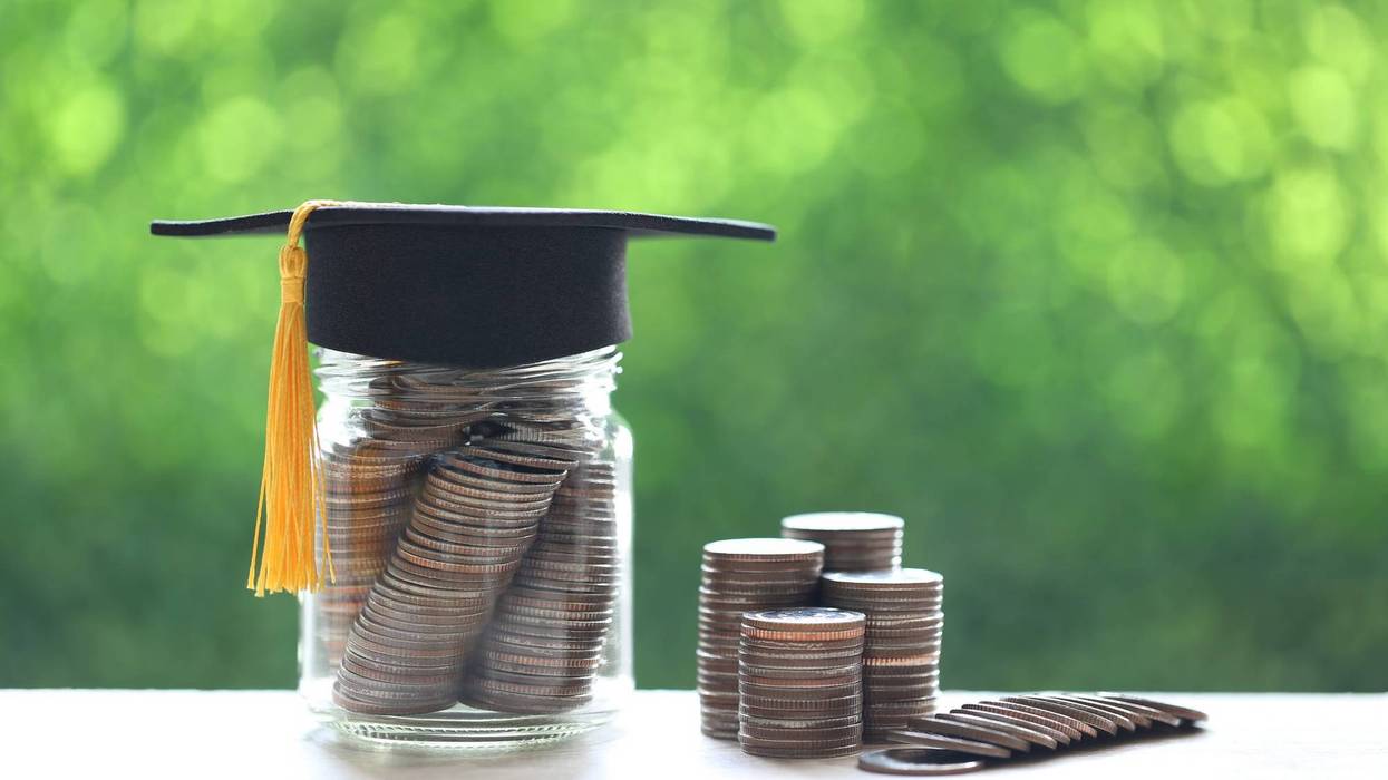 Graduation hat on the glass bottle with Stack of coins money on nature green background.