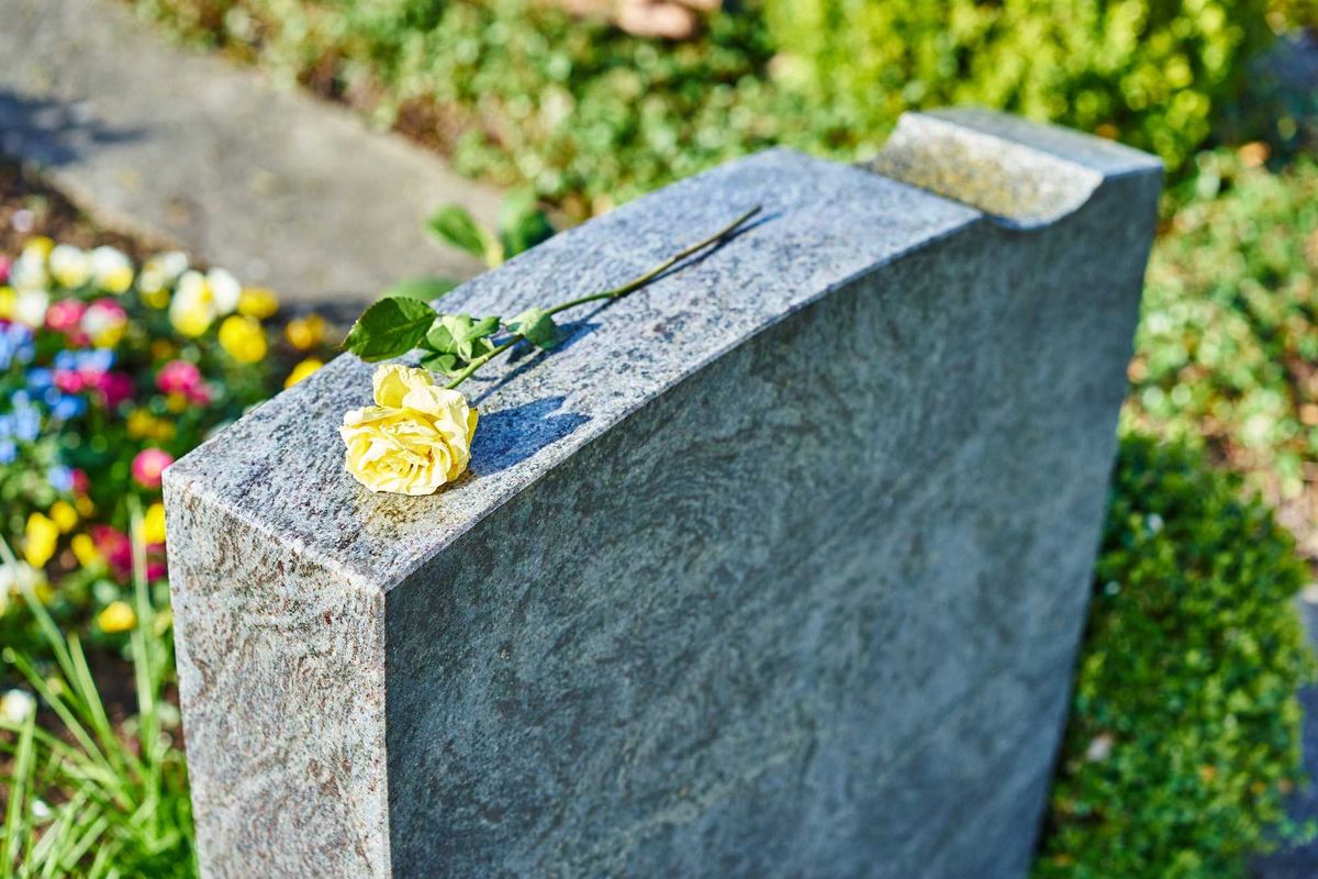 Gravesite headstone with a flower on top.