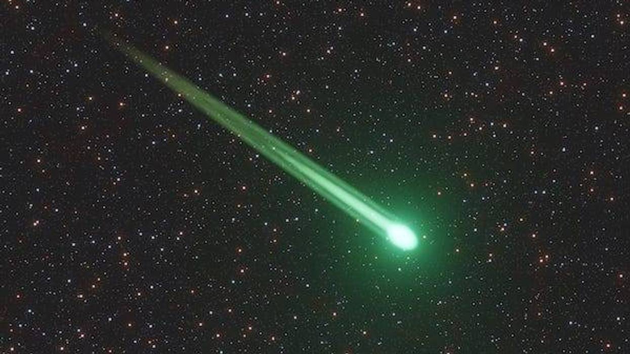 Green meteor or comet flying through the starry sky