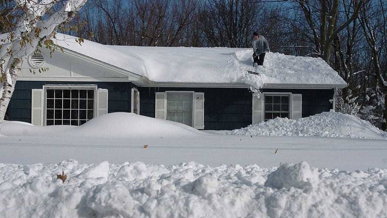 Greg Mitri shovels snow from his roofe in the Buffalo, New York suburb of Lakeview November 20, 2014. The record setting Lake effect snowstorm dumped up to six feet of snow in less than 24 hours closing a one hundred mile section of The New York State Thruway as well as other major roads around Buffalo.