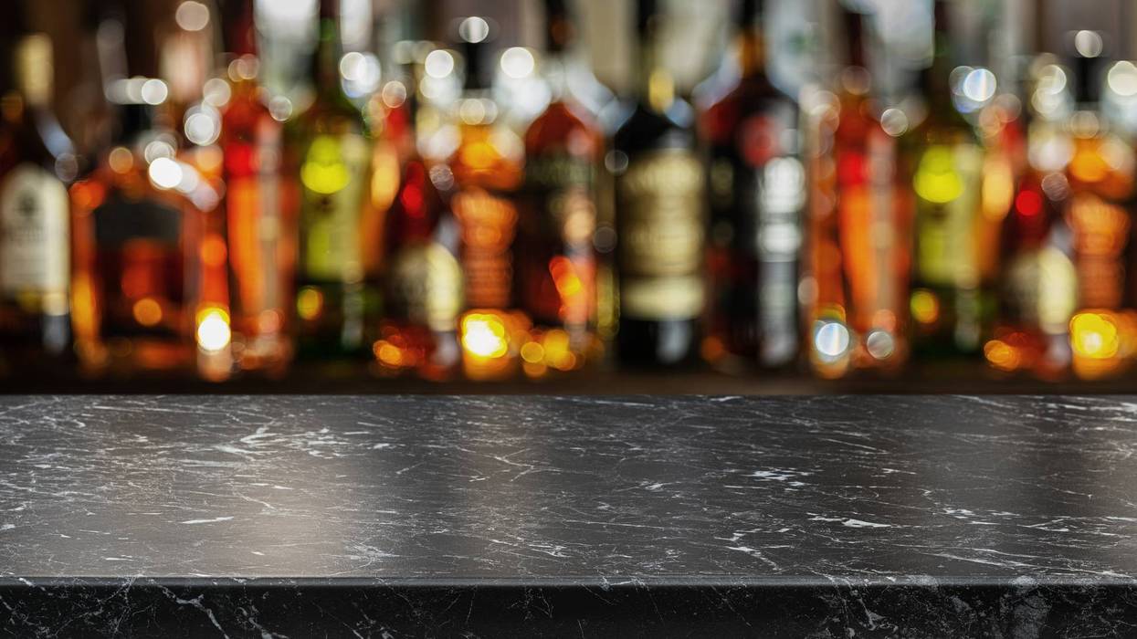 Grey table top and beautiful bokeh shelves with alcohol bottles at the background. Bar concept.