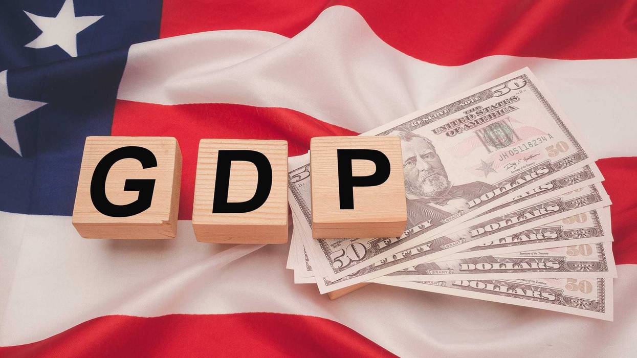 Gross Domestic Product (GDP) of the United States. Close-up of wooden cubes with the letters GDP on US dollars banknotes over the American flag background. Business and growth of GDP concept