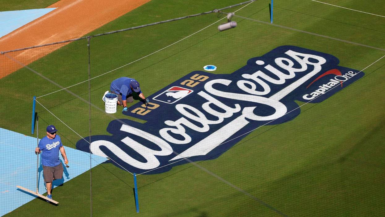 Grounds crew members paint the 2025 World Series logo on the infield during a World Series workout day at Dodger Stadium on October 26, 2025 in Los Angeles, California.