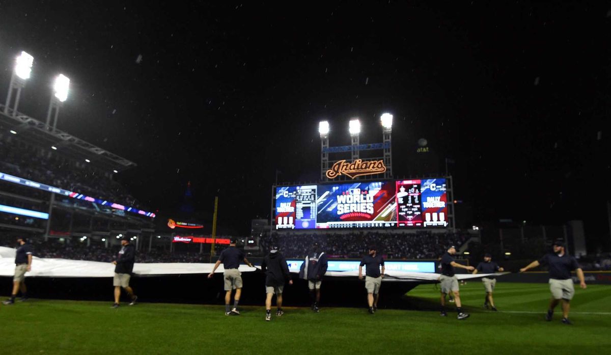 Grounds crew members pull the tarp on the field in the 10th inning as rain falls in game seven of the 2016 World Series between the Chicago Cubs and the Cleveland Indians at Progressive Field.