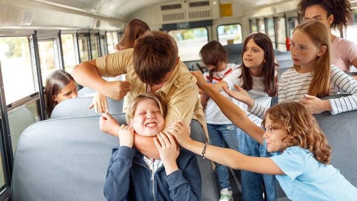 Group of children classmates going to school by bus boy strangling kid punching angry while others trying to stop him from violence