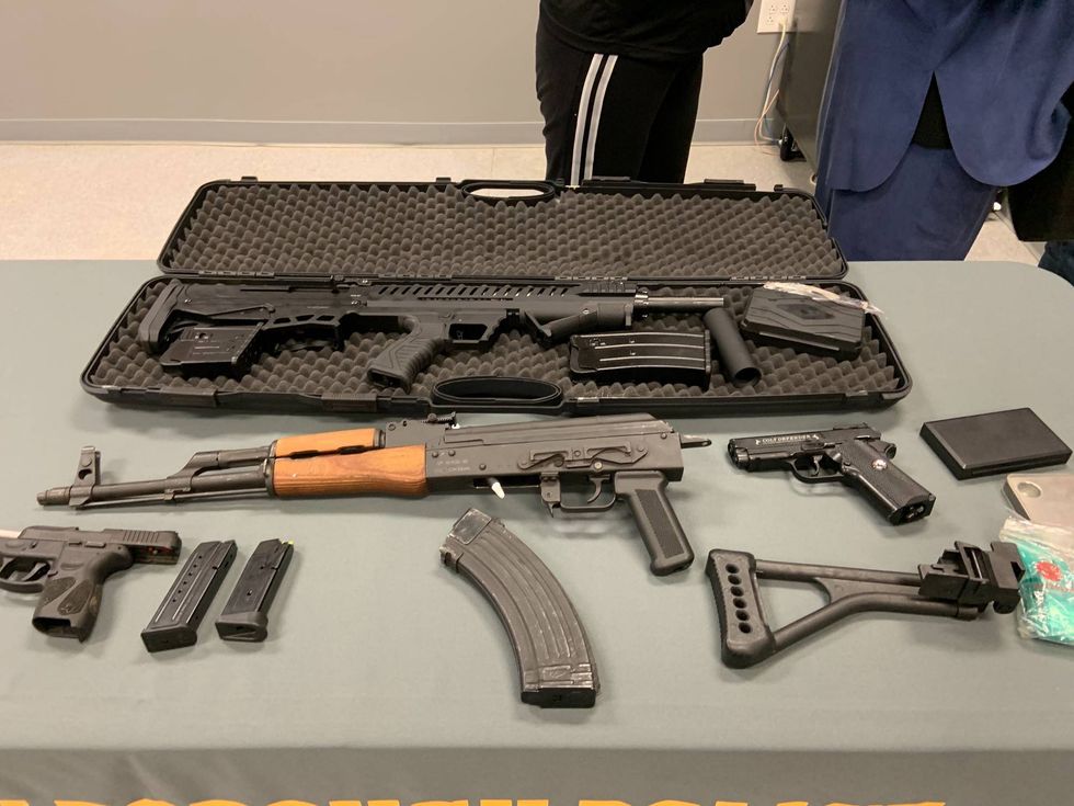 Guns seized from a home where, police say, shots were fired through the wall separating two rowhouses.