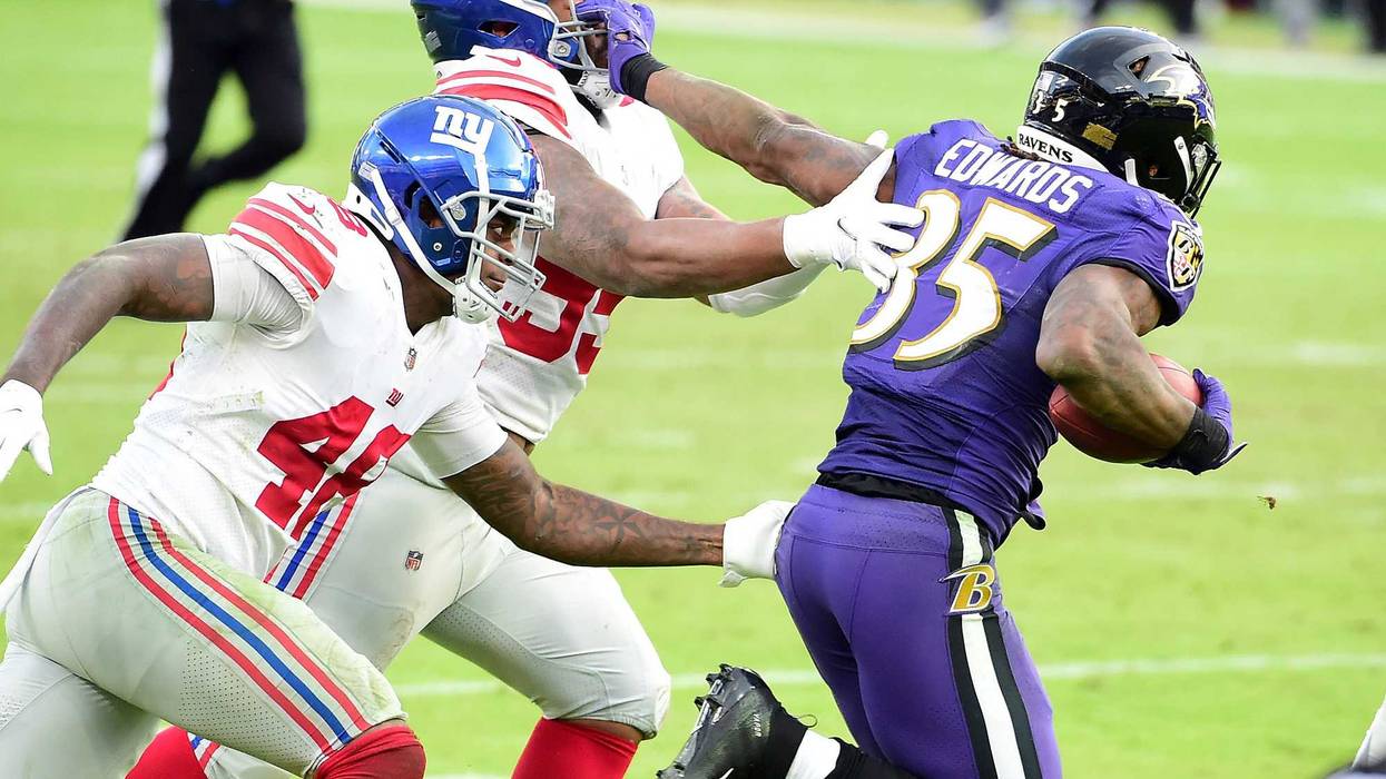 Gus Edwards stiff-arms a Giants defender during Sunday's 27-13 win.