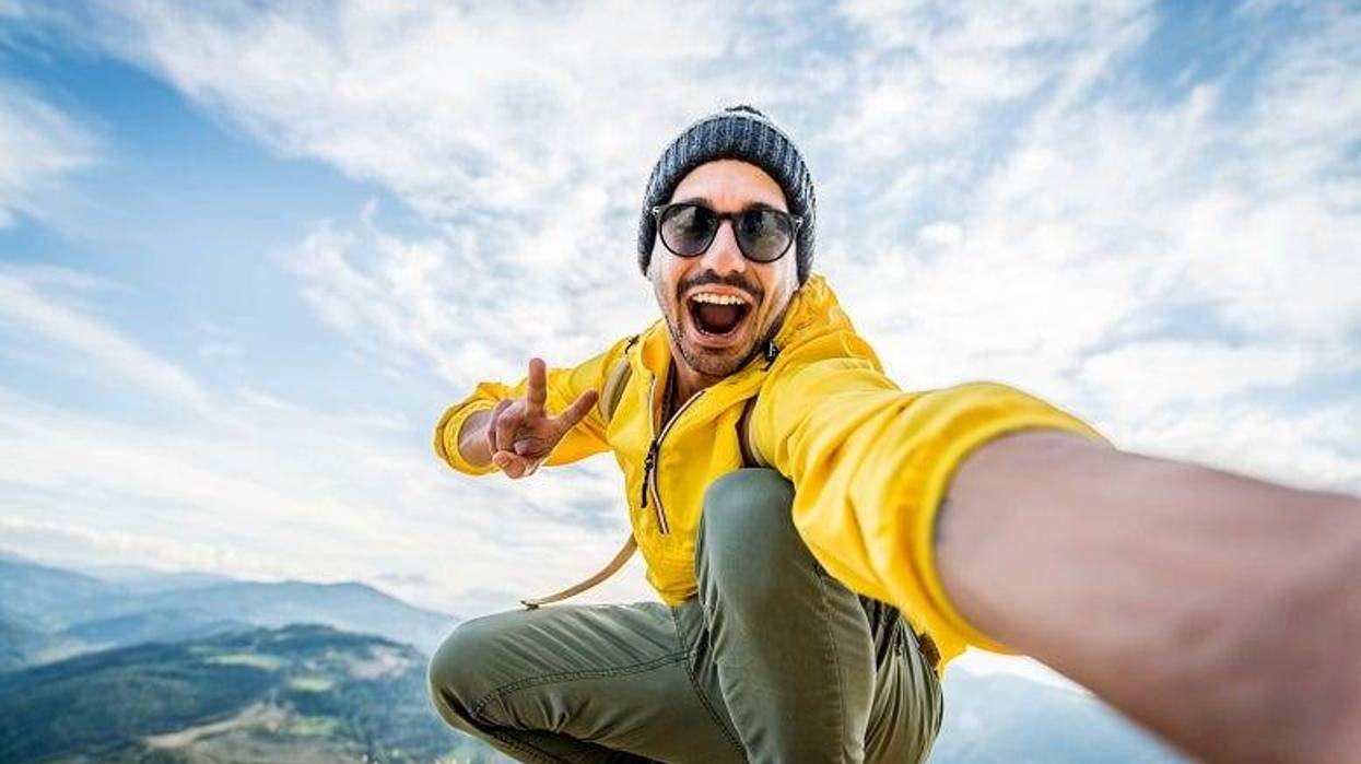 Guy taking selfie on top of mountain