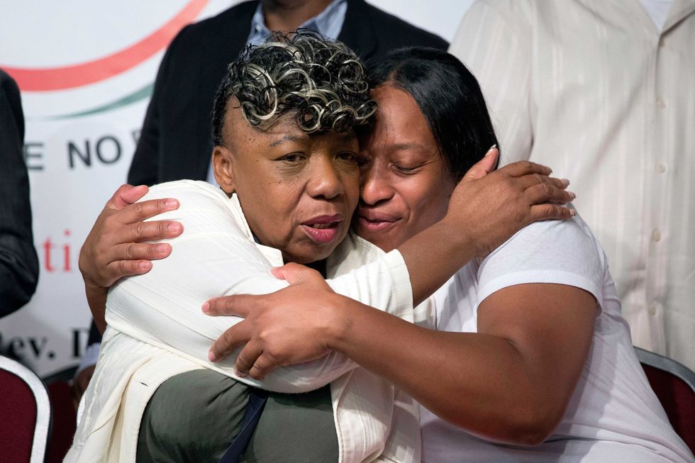 Gwen Carr, left, mother of Eric Garner, and his sister Ellisha Garner, hug during a rally at the National Action Network headquarters, July 26, 2014, in New York