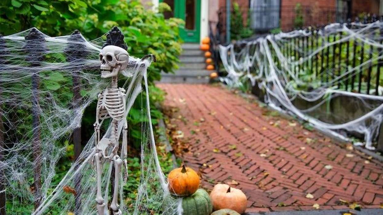 Halloween decorations on a home; Skeleton and spider web on a fence