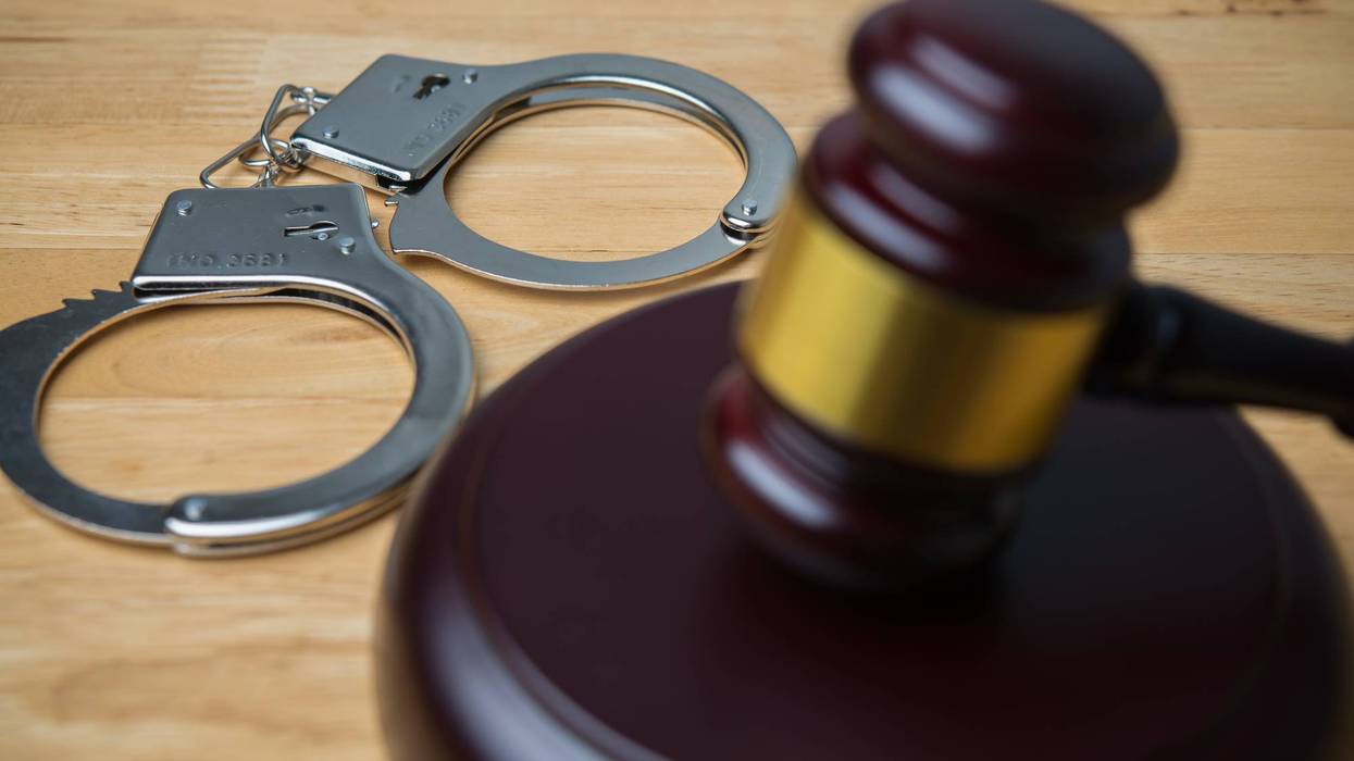Hammer judge gavel and handcuffs in courtroom on wooden table background.