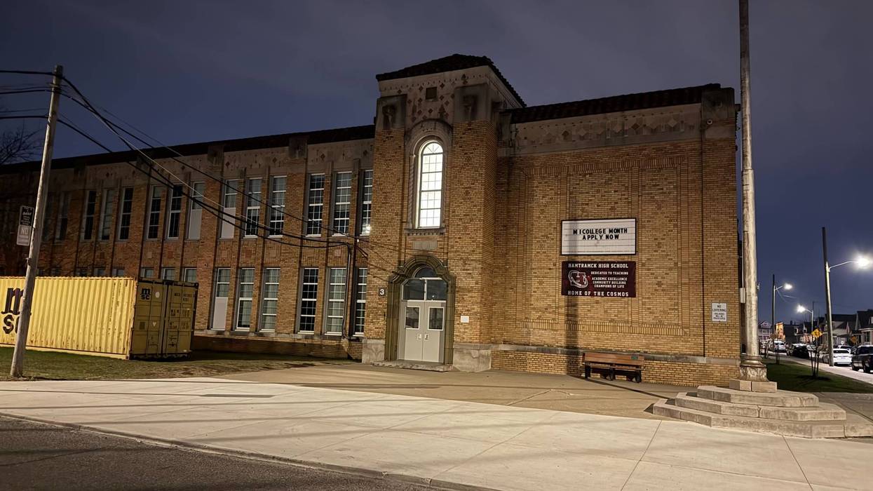 Hamtramck High School: brick building at night with lit windows, signs, yellow containers.