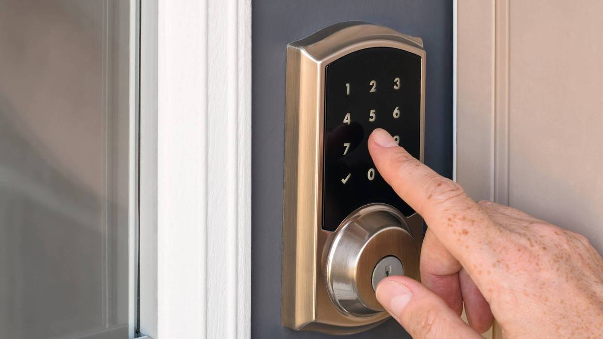 Hand entering code into home door lock