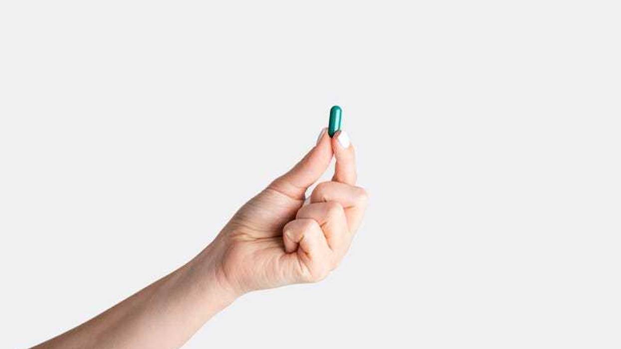 Hand holding a pill.