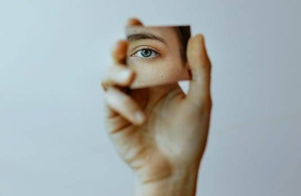 Hand Holding Mirror and Eye Reflected In It