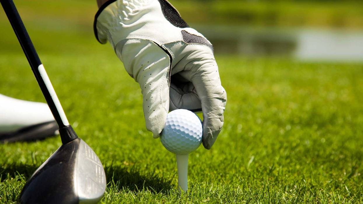 Hand places golf ball on tee