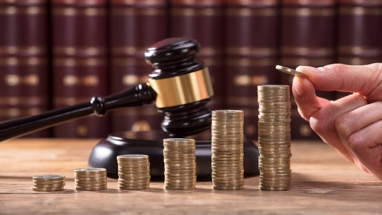hand placing coin on stack with judge's gavel in the background