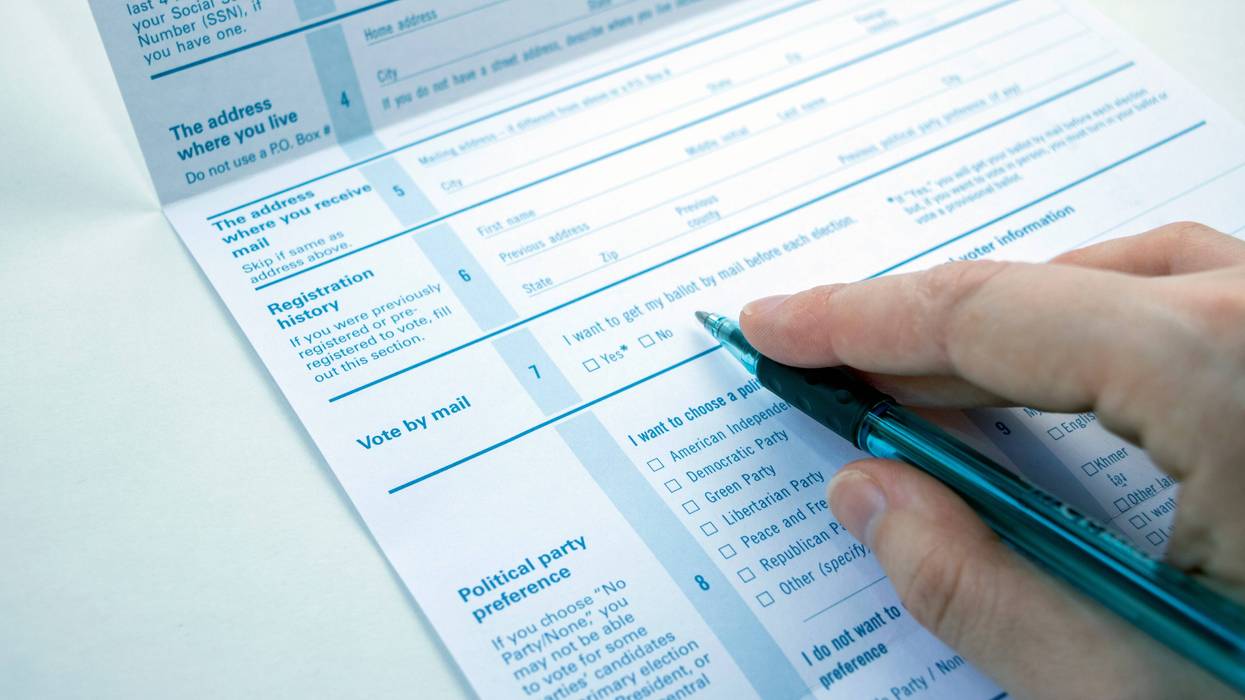 Hand with pen filling out voter registration form