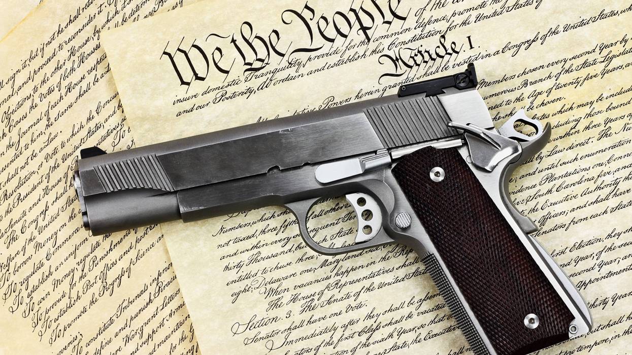 Handgun lying over a copy of the United States constitution with the words "We the People" visible.