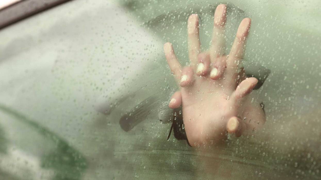 Hands clasped in a car window.