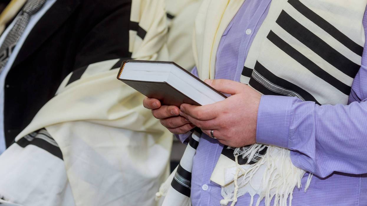 Hands holding a Jewish prayer book