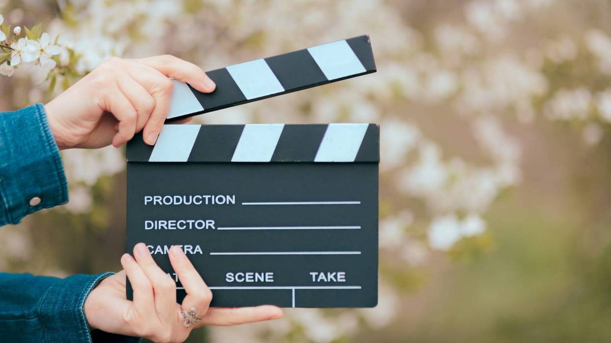 Hands Holding Film Slate Cinema Clapper on Spring Blooming Background