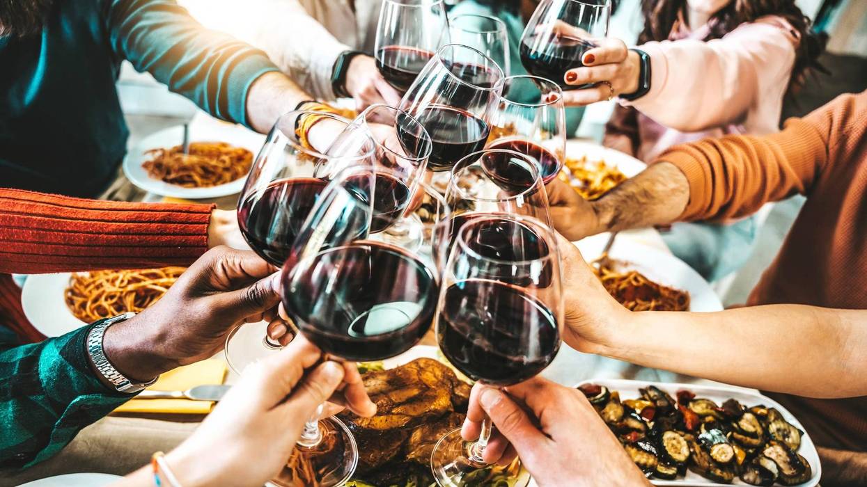 Happy friends toasting red wine glasses at dinner party - Group of people having lunch break at bar restaurant - Life style concept with guys and girls hanging out together - Food and beverage - stock photo