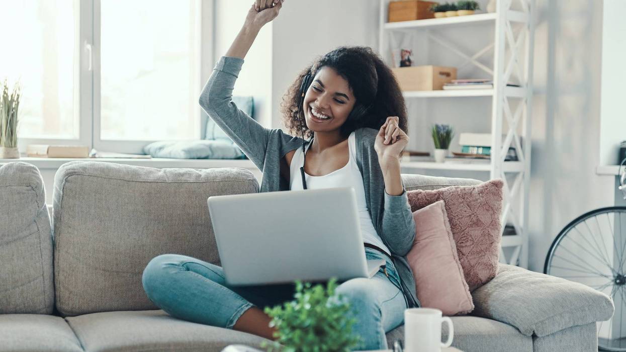 Happy young woman in casual clothing enjoying music and smiling while resting at home