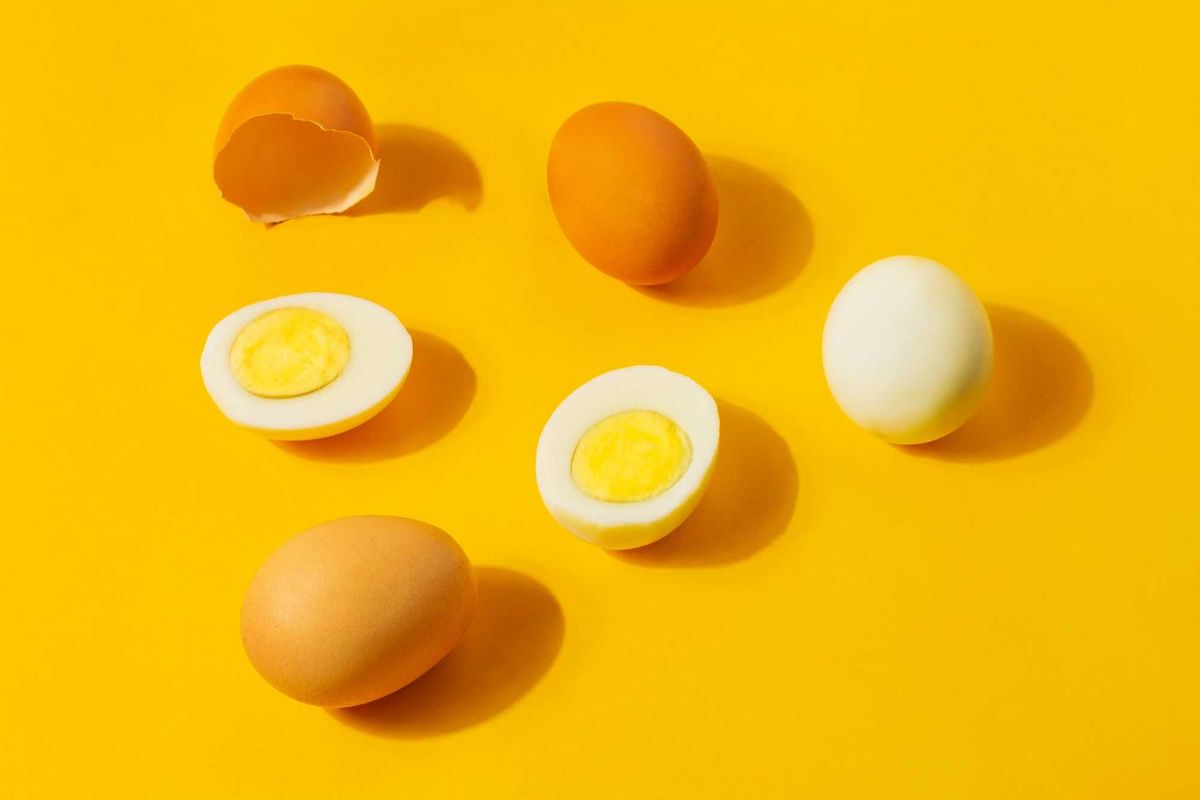 Hard boiled eggs and brown shells on a clean yellow background.