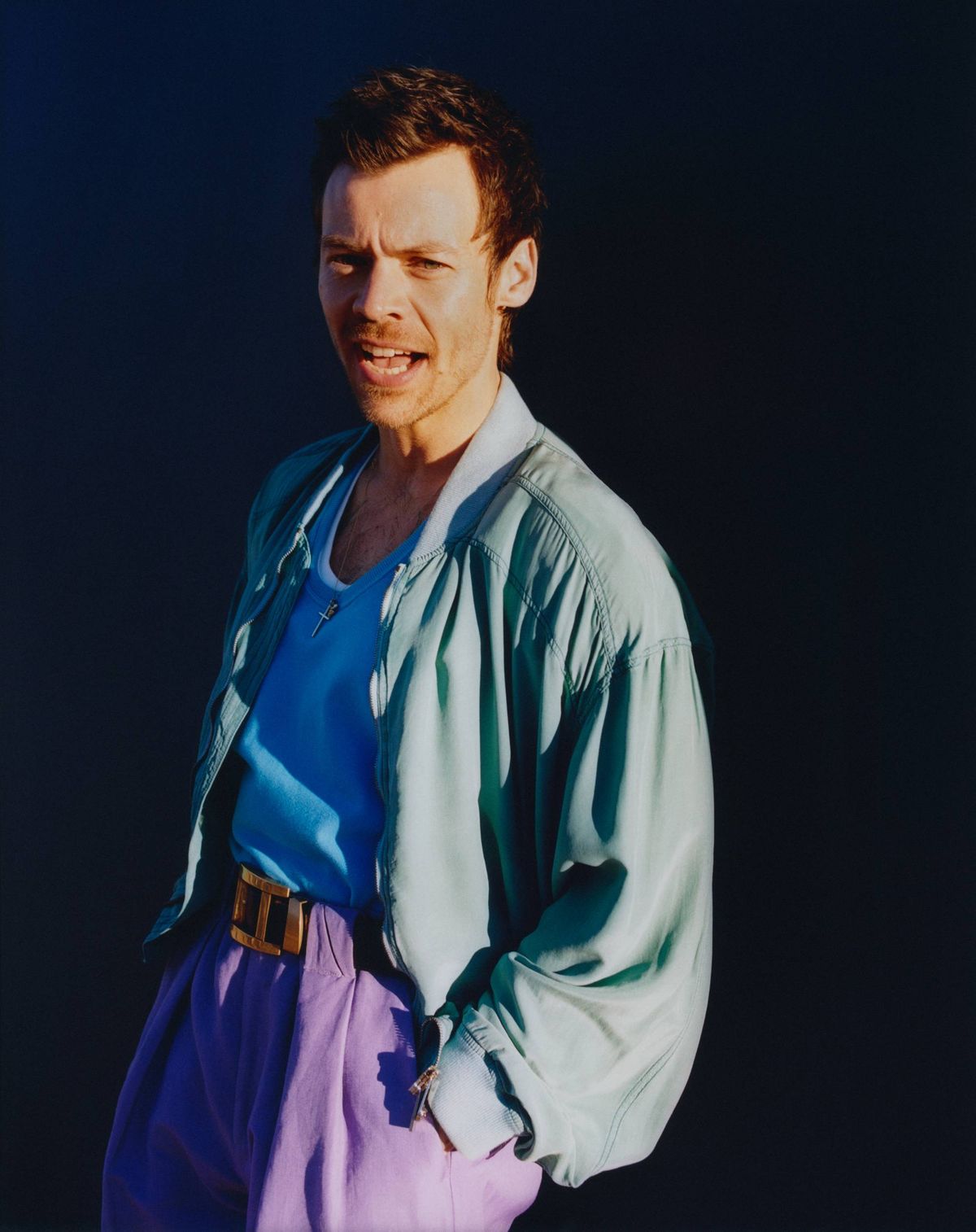 Harry Styles in mint jacket, blue shirt, purple pants, gold belt, looking at viewer with mouth open