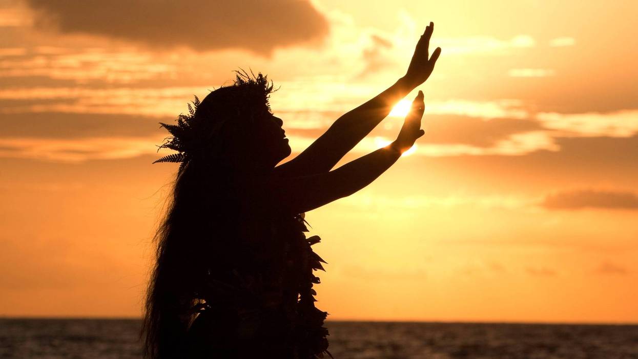 Hawaiian hula dancer performs a hula in front of the tropical sunset.