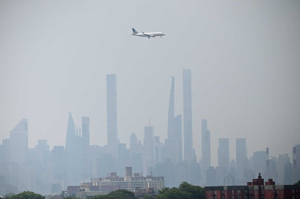 Haze and smoke from Canadian wildfires hover over the Manhattan skyline as a Continental Airlines plane makes a final approach at LaGuardia Airport in Queens on June 29, 2023
