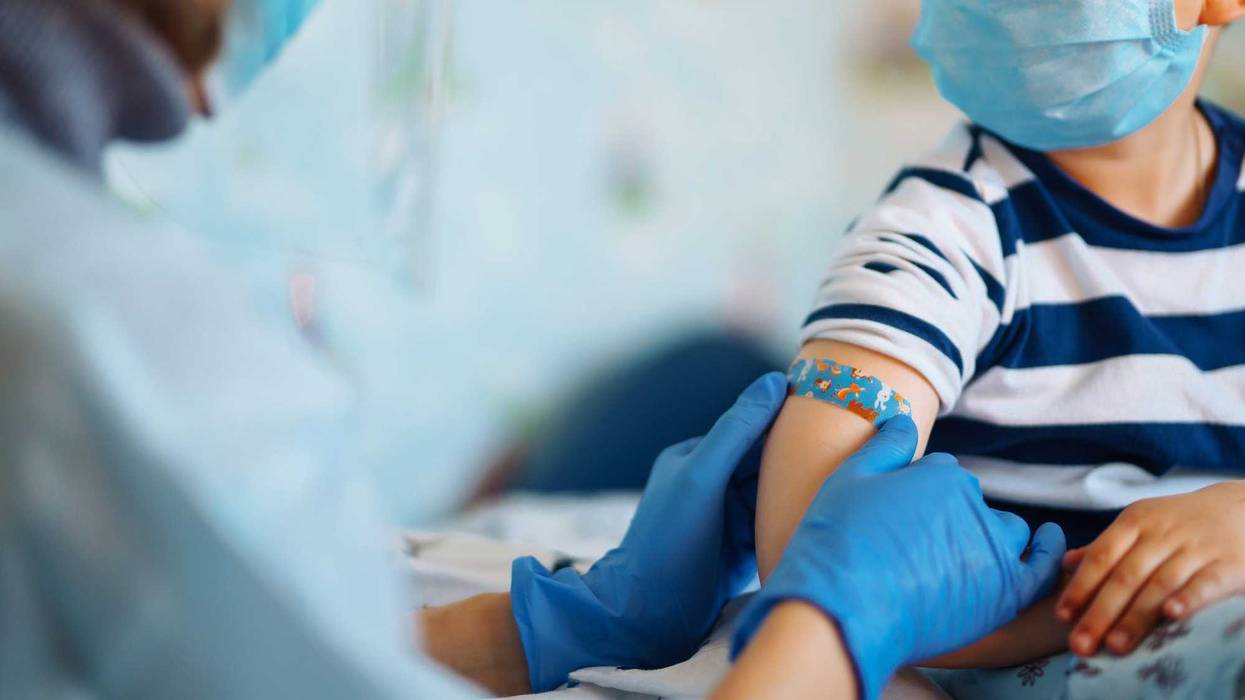 Health care professional putting a bandage on a child after they receive a vaccine shot.