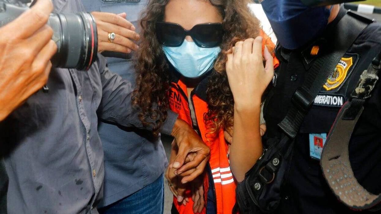 Heather Mack of Chicago, Ill., center, escorted by Indonesian immigration officers to Immigration detention center in Jimbaran, Bali, Indonesia on Friday, Oct. 29, 2021. The American woman convicted of helping to kill her mother on Indonesia's tourist island of Bali in 2014 walked free from prison Friday after serving seven years of a 10-year sentence and will be deported to the United States.