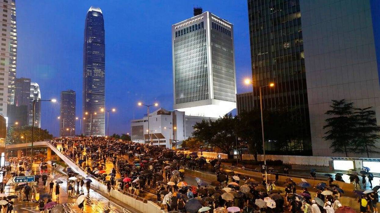 Heavy rain fell on tens of thousands of umbrella-toting protesters Sunday as they marched from a packed park and filled a major road in Hong Kong.