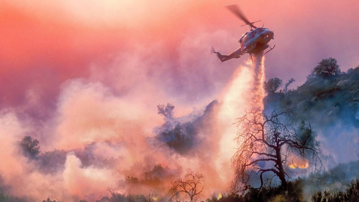 helicopter drops water on wildfire