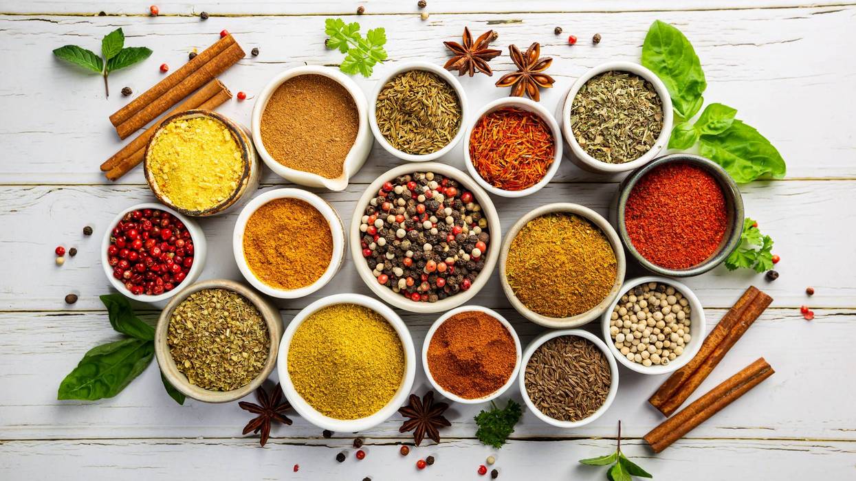 Herbs and spices in bowels over white wooden background