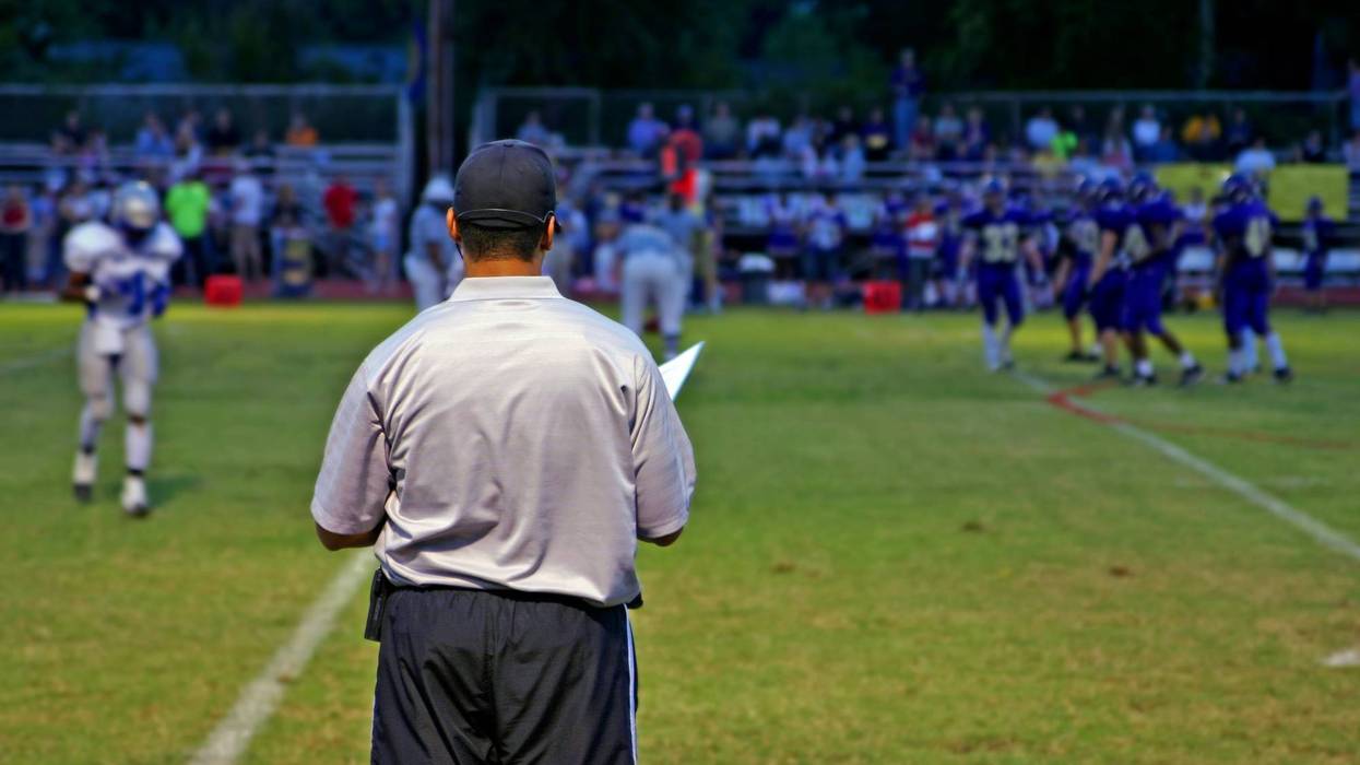 High School football coach watches his team play