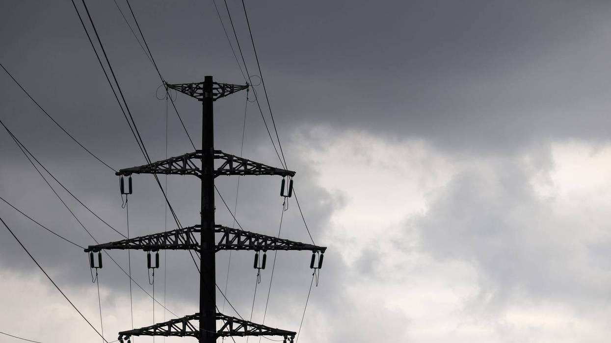 High voltage tower silhouette with electrical wires on storm sky background with dark clouds - stock photo