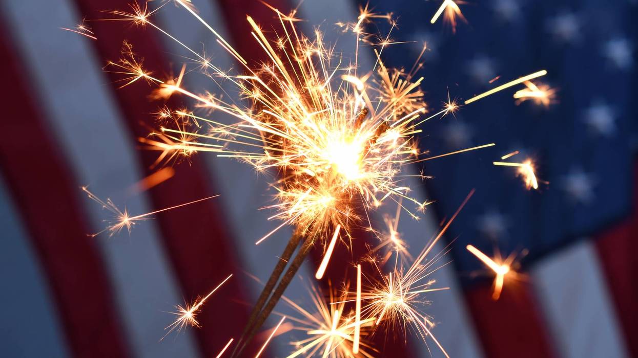 Holding a sparkler in front of an American Flag to celebrate the 4th of July Independence Day