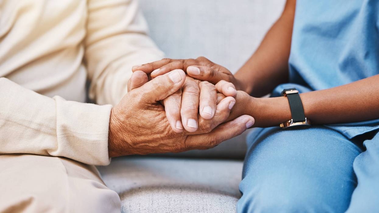 Home care nurse holds senior patient's hand
