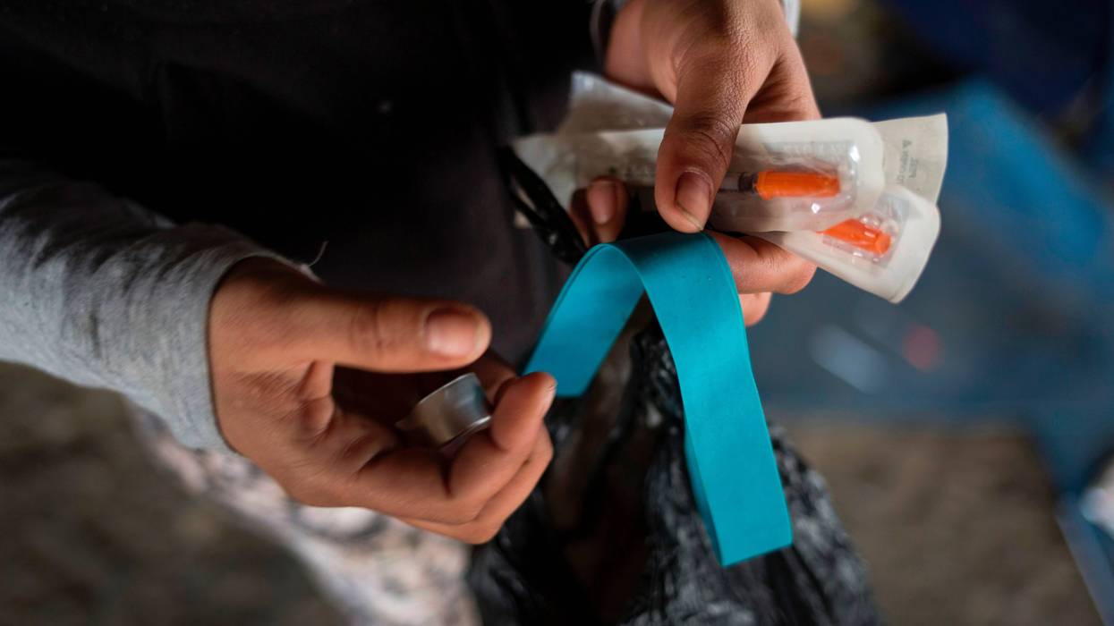 Homeless heroin user shows her kit of clean needles, mixing cap and tourniquet in Kensington