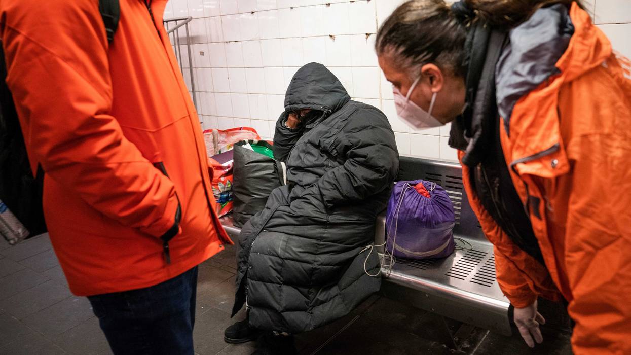 Homeless Outreach personnel reach out to a person sleeping on a bench in the Manhattan subway system, Monday, Feb. 21, 2022, in New York.