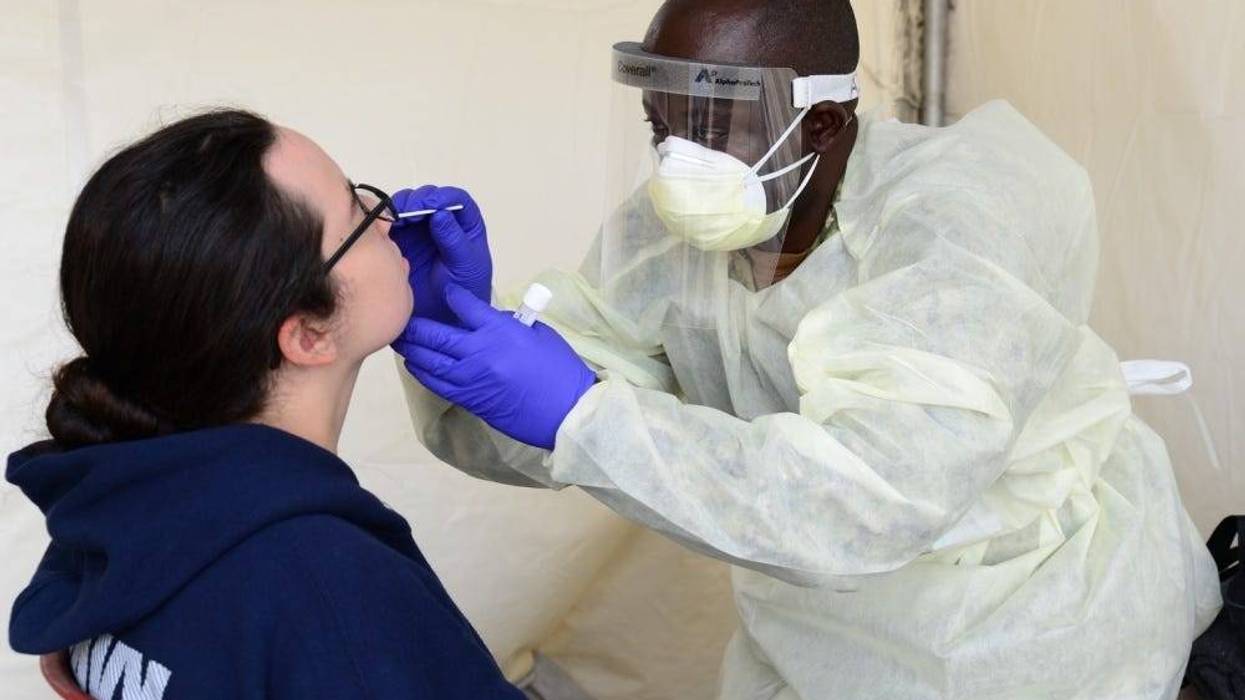 Hospital Corpsman 3rd Class Rene Azombi, a Navy reservist temporarily assigned to Navy Medicine Readiness and Training Command Great Lakes (NMRTC) to assist with COVID-19 screening efforts, conducts a nasal swab on a recruit.