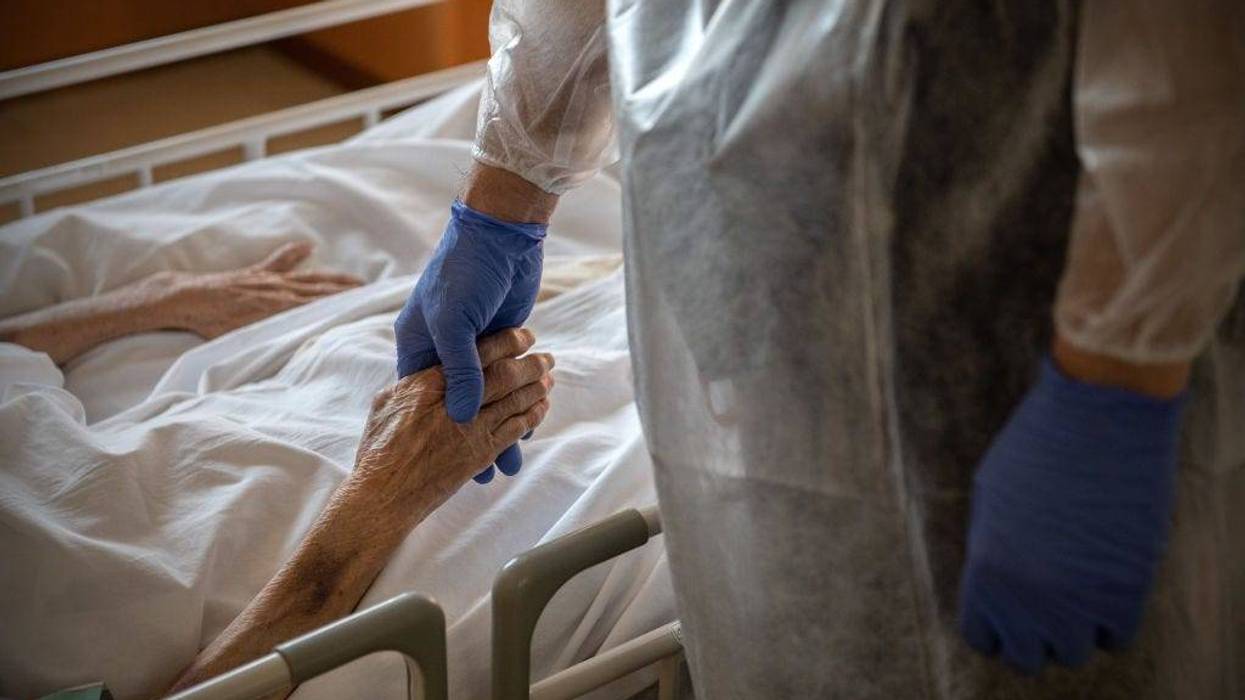 Hospital Director, Doctor Yutaka Kobayashi, holds the hand of a 94-year-old coronavirus patient on a coronavirus ward at Sakura General Hospital on February 10, 2021 in Oguchi, Japan.