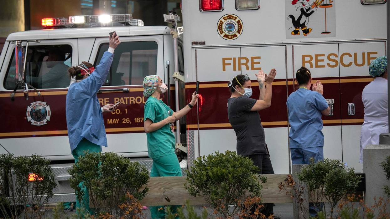 Hospital workers cheer as first responders pass by the Westchester Medical Center in a caravan of sirens and lights on April 14, 2020 in Valhalla, New York.