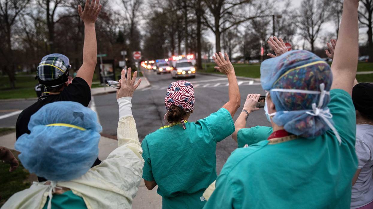 Hospital workers wave and cheer outside the Westchester Medical Center as first responders pass by in a caravan of sirens and lights on April 14, 2020 in Valhalla, New York.